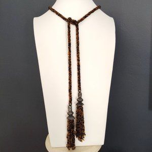 Long, single strand seed bead necklace with metal accent and tassels